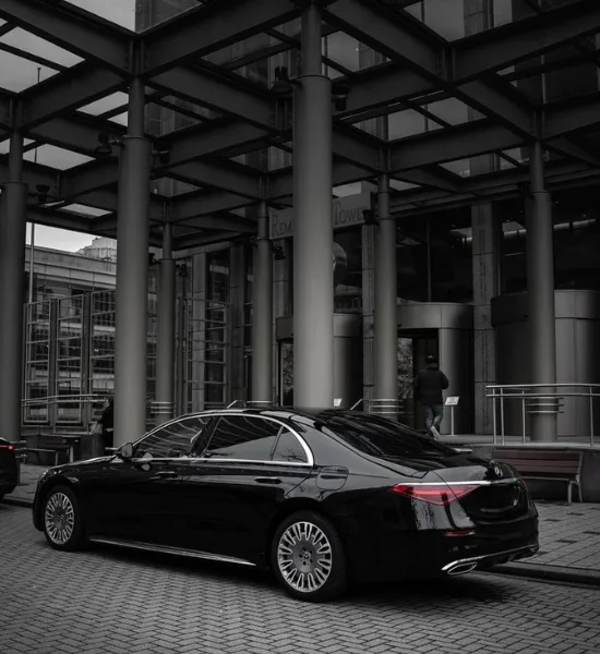 Black luxury sedan outside corporate building entrance