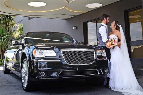 Bride and groom beside black wedding limousine Bride and groom beside black wedding limousine