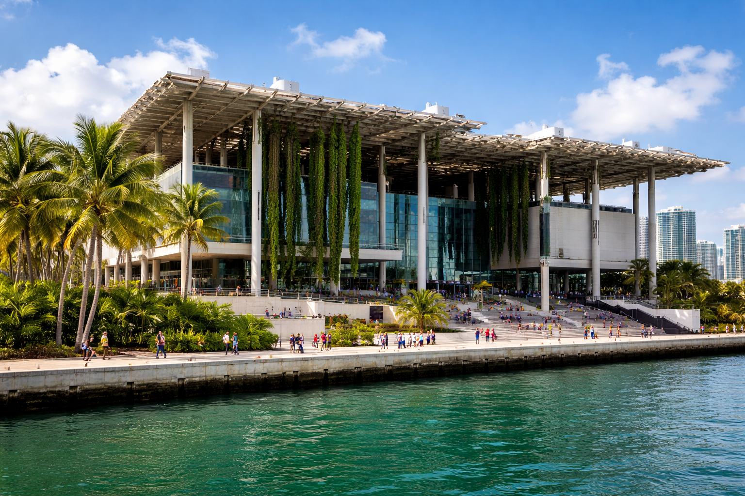 Perez Art Museum Miami building with waterfront, palm trees, and visitors along Biscayne Bay promenade.