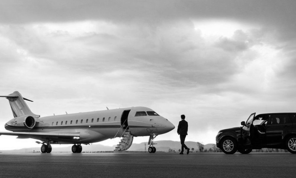 Private jet on runway with luxury SUV and passenger walking