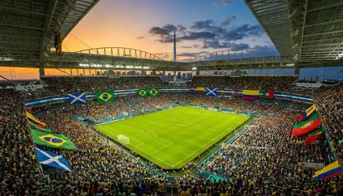 Aerial view of a packed soccer stadium at sunset with international flags