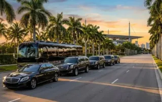 Black luxury vehicles and charter coach parked along a palm-lined Miami boulevard