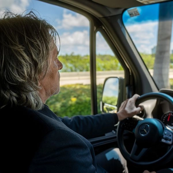 man with long blonde hair driving a vehicle man with long blonde hair driving a vehicle