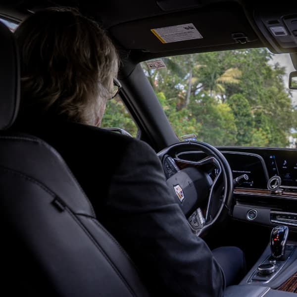 professional chauffeur driving luxury vehicle from back view
